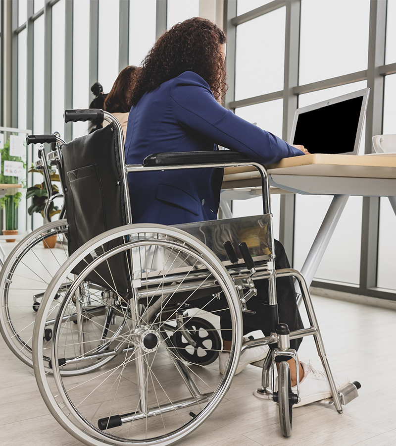 persona con sedia a rotelle che lavora ad una scrivania ergonomica